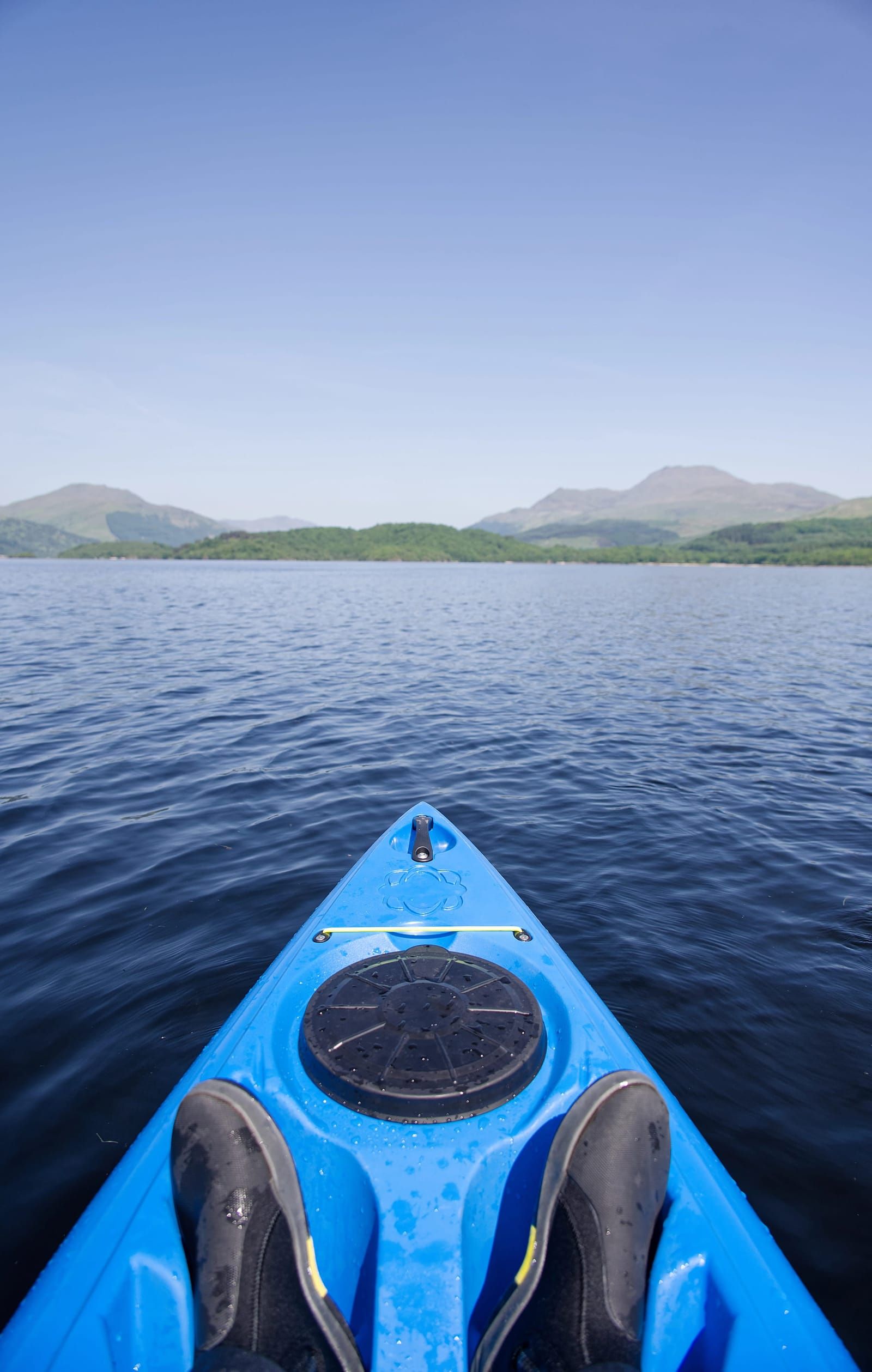 Kayaker on calm water with mountains in the background
