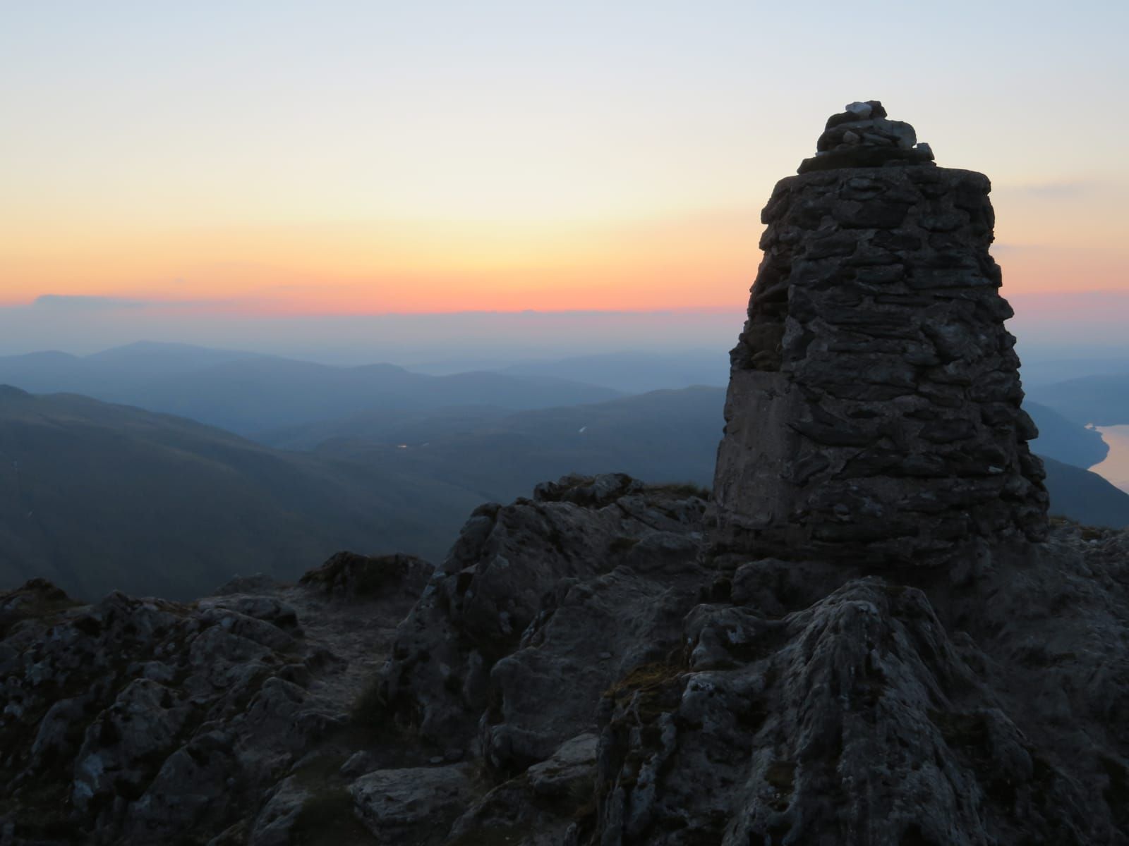 Dawn light provides a colourful backdrop for the summit cairn of Ben Lawers as sunrise nears